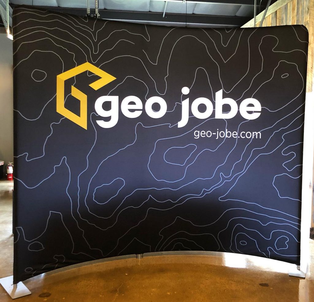 Fabric stretched across metal frame with white contour lines and the GEO Jobe logo printed on it.