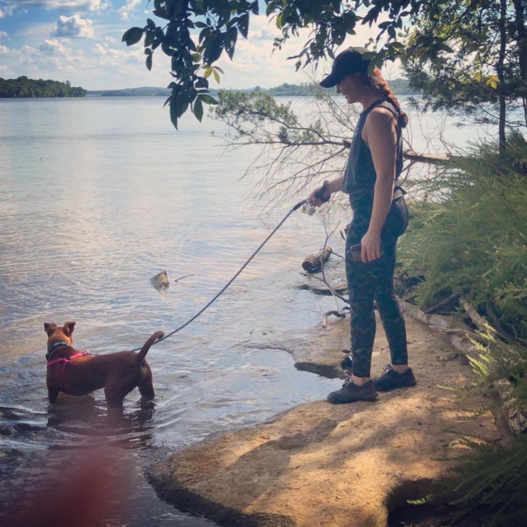A photo of Carrie and her dog Missy Sue hiking by a lake 